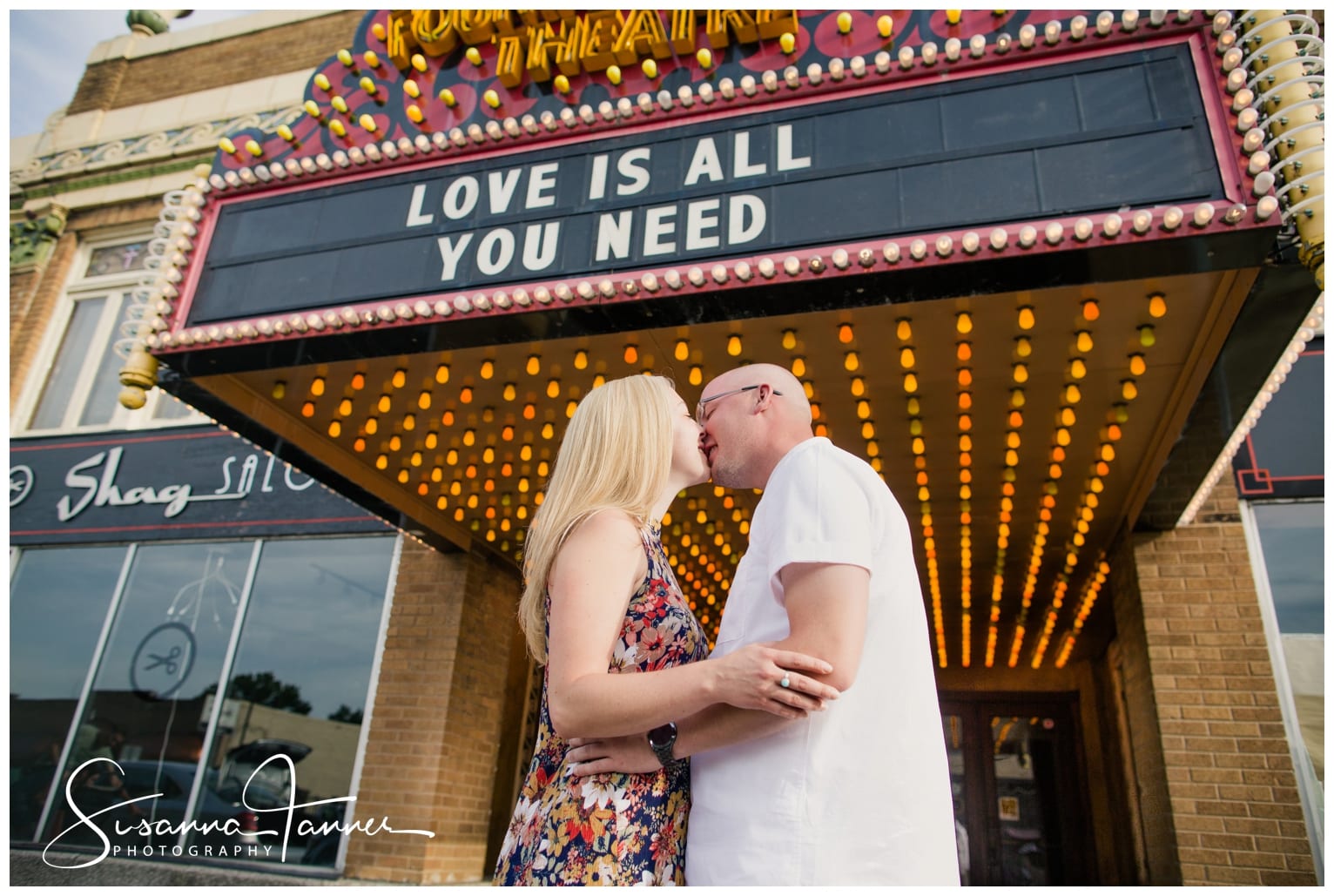 Fountain Square Indianapolis Photography Engagement Session Couple in front of Fountain Square theatre. Marquee reads "Love is all you need"