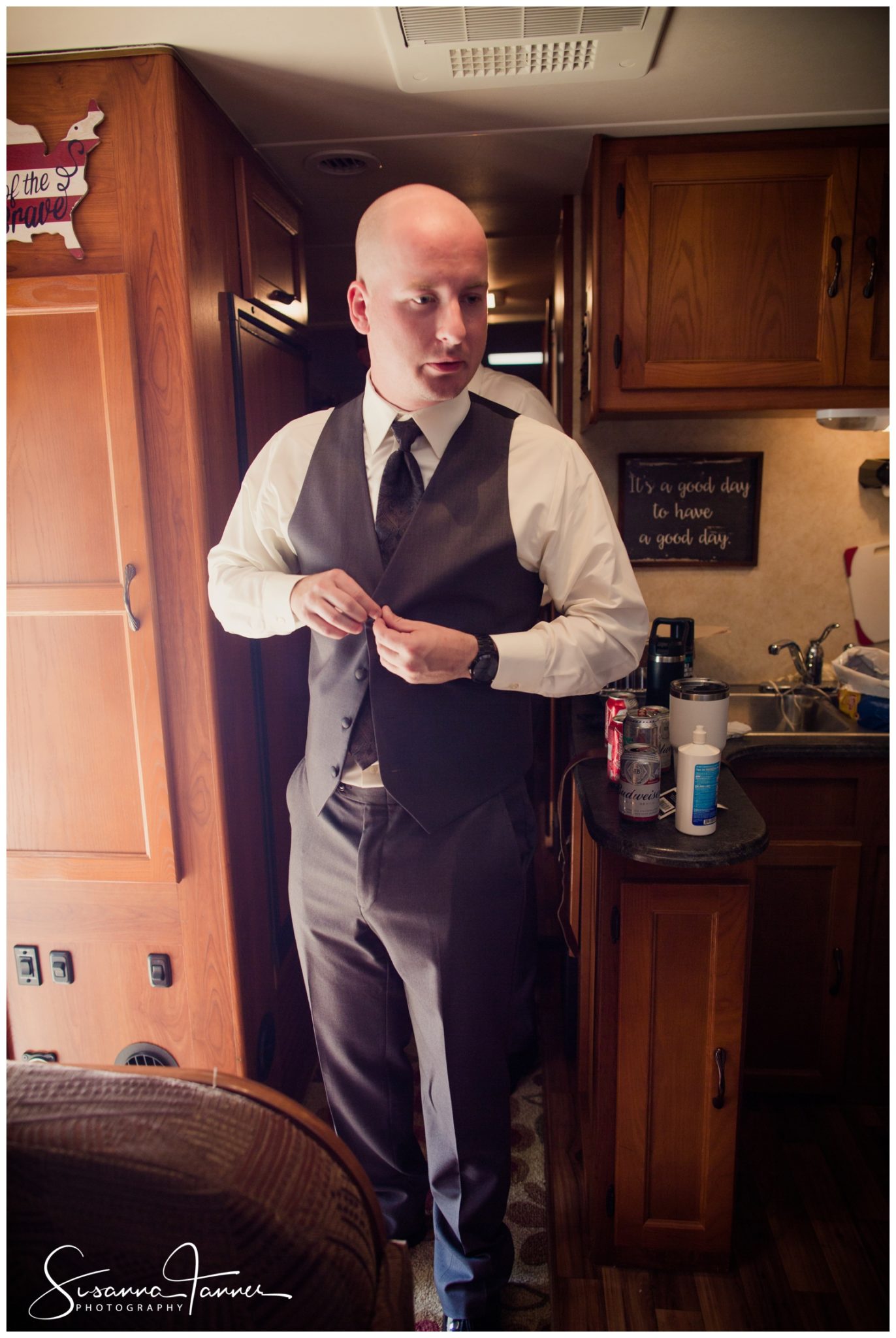 Indianapolis Outdoor Wedding, groom buttoning vest while inside the RV