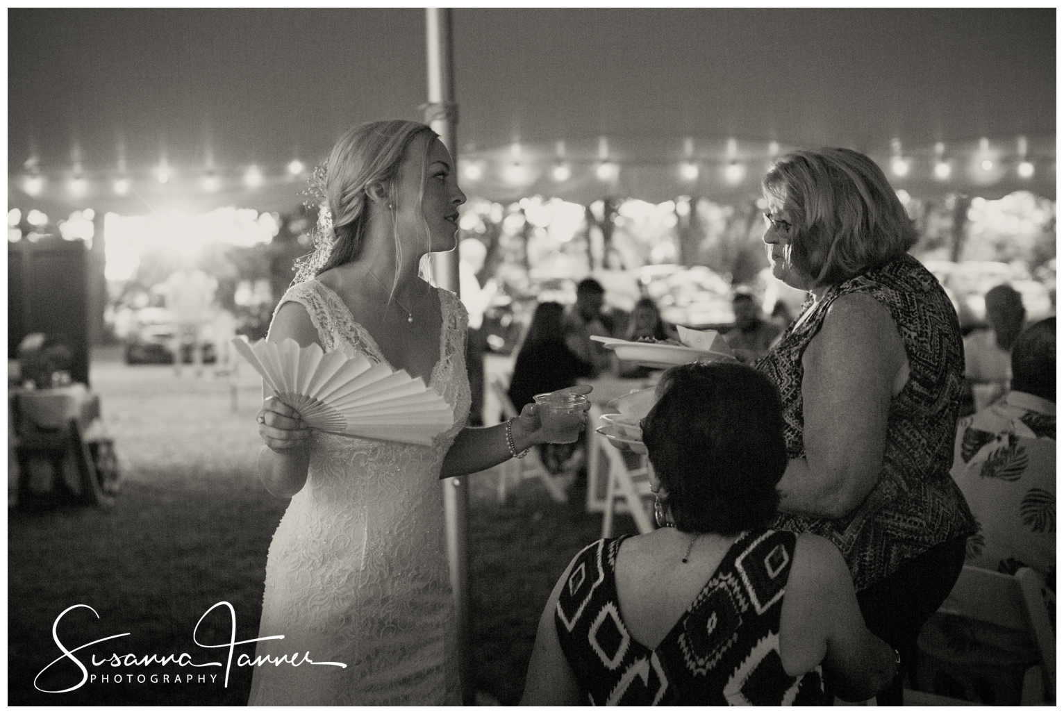 Indianapolis Outdoor Wedding, bride talking to guests holding a fan to cool her off