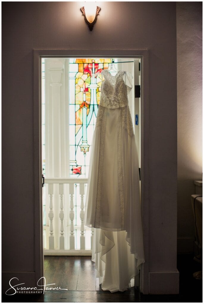 The Transept, Cincinnati OH wedding, wedding dress hanging from doorway with stained glass behind it. 