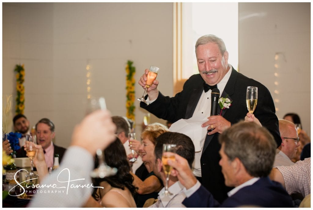Father of the bride giving a toast and holding up champagne glass