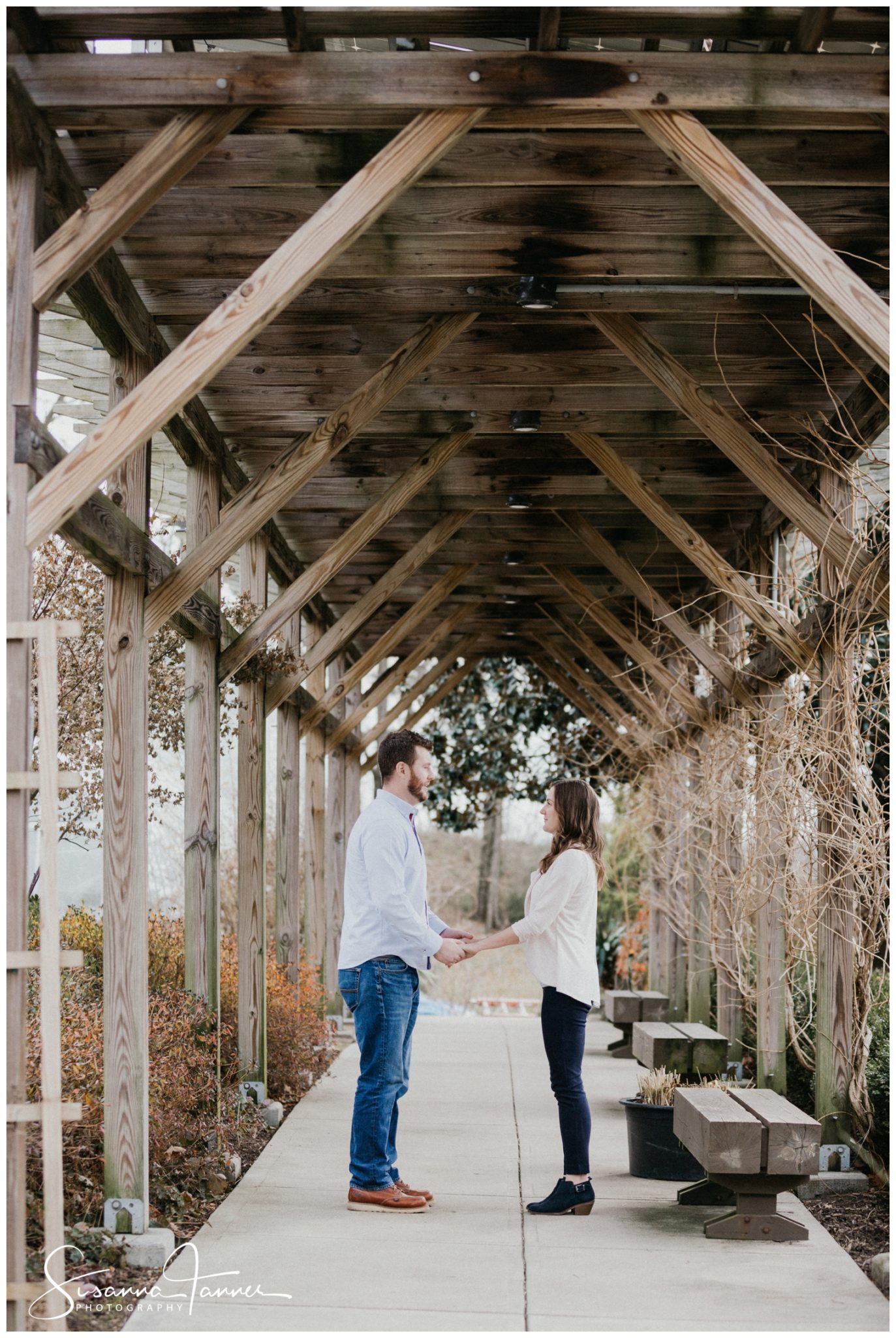 Cincinnati Krohn Conservatory Engagement Photography, couple face each other standing, hold hands and look at each other in outdoor landscaped patio.