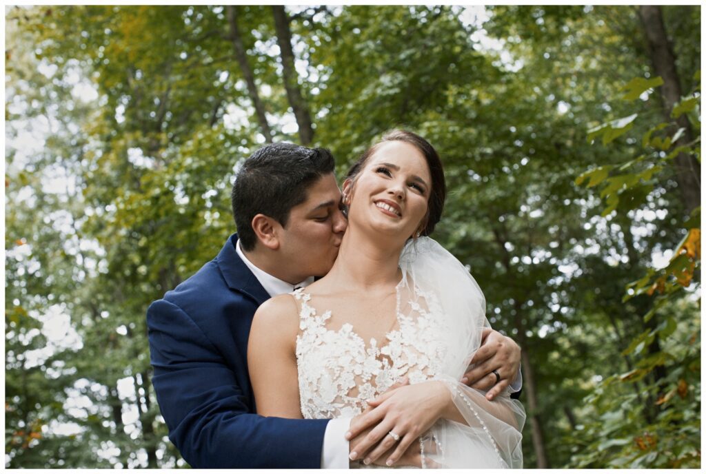 groom kissing bride's neck outside The Wilds Wedding Venue, Bloomington, Indiana