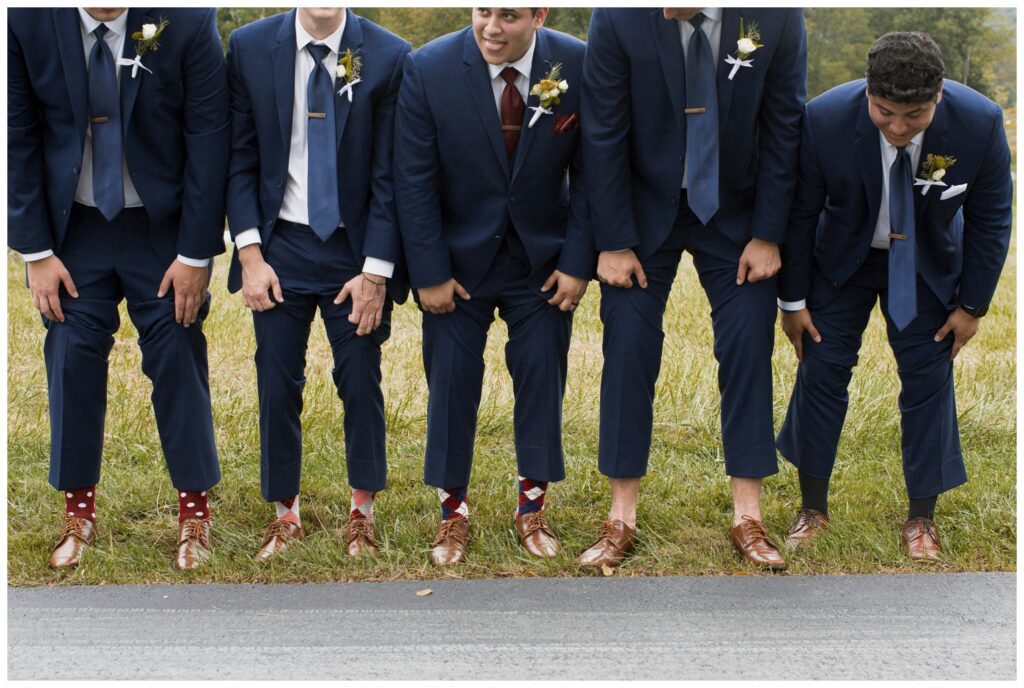 groomsmen laughing and showing off their different socks