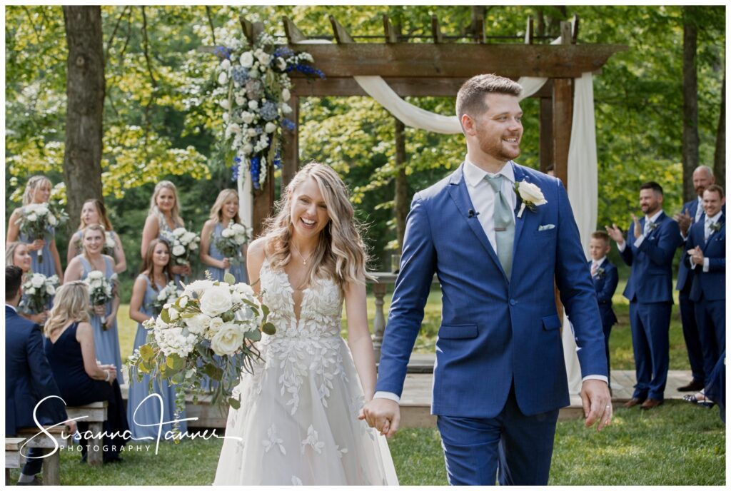 Couple smiling as they walk aisle after being married