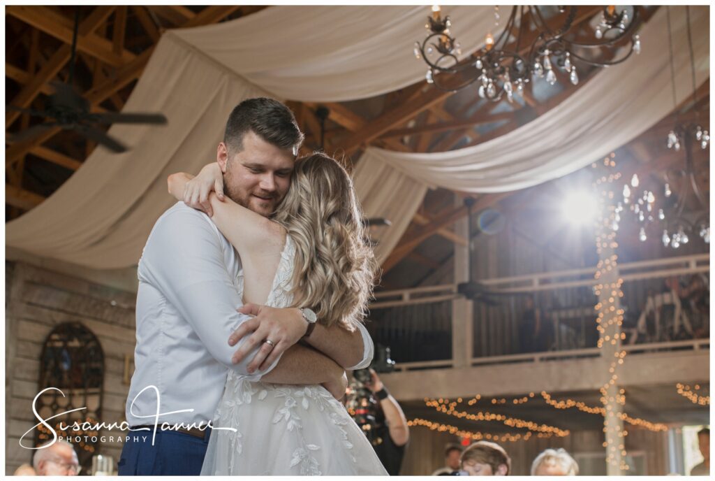 bride wrapping her arms around groom's neck during first dance