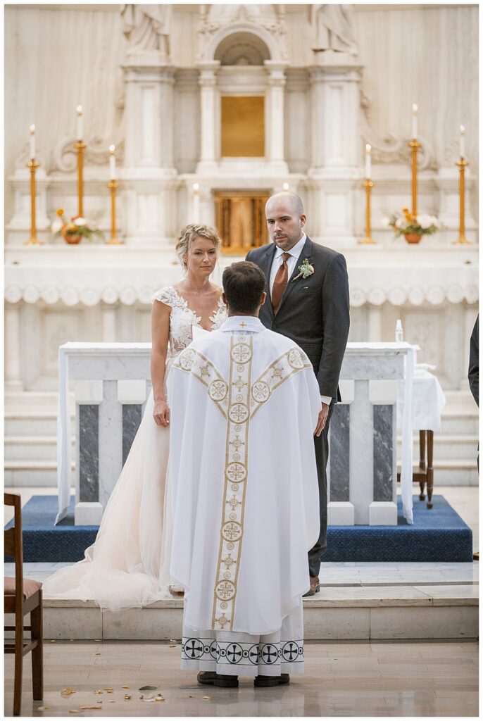 bride and groom stand before priest