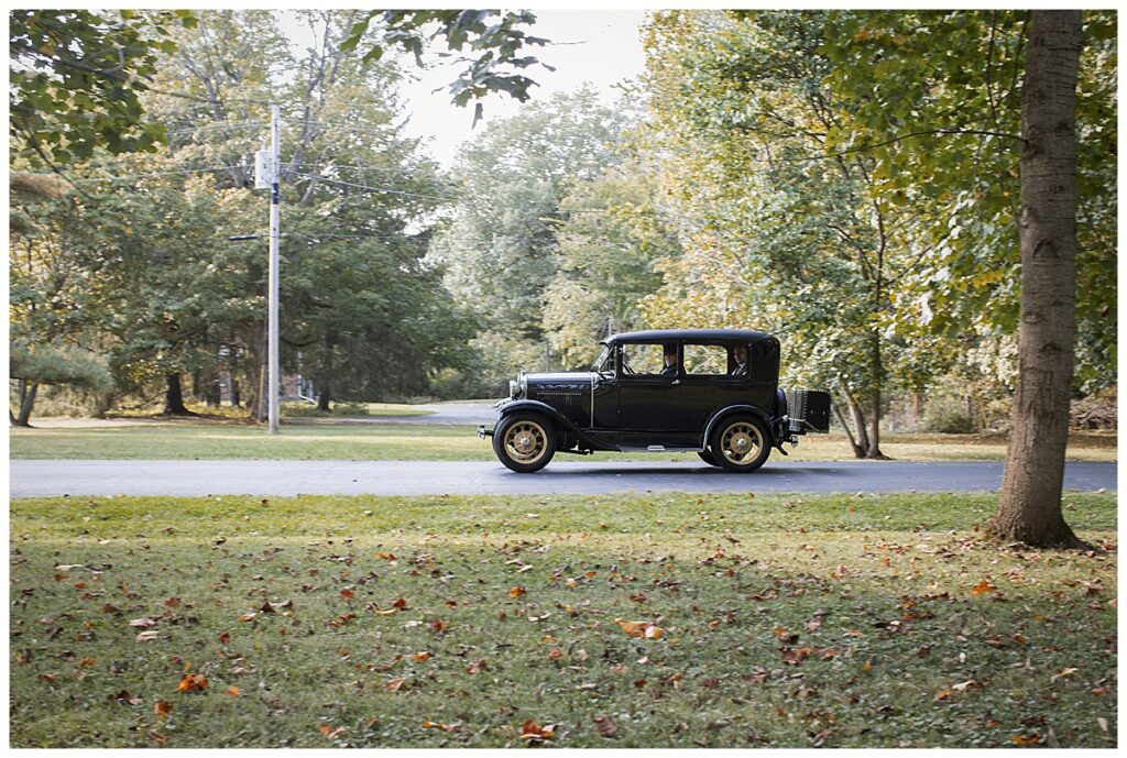antique car drives couple to outdoor wedding venue, Richmond, IN